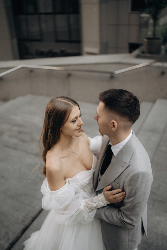 Above view of beautiful bride wearing wedding dress having photoshop with handsome groom. Beloved couple getting married, looking at each other. Concept of wedding and marriage.